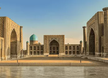 Ornate Islamic architecture with domes and tall minarets reflecting in a courtyard pool.
