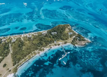 Aerial view of a small tropical island surrounded by bright blue waters.