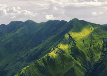 Lush green mountains covered in sharp ridges under cloudy skies.