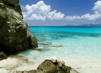 Rocky tropical shoreline with turquoise waters and white sand.