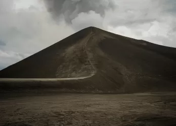 Dark volcanic cone with smoke rising from the crater.
