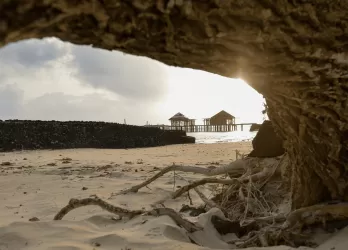 A sandy beach framed by a rocky cave opening.