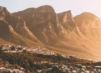Rugged golden mountains with a city nestled at their base.