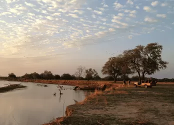 A large body of water sitting next to a lush green field.